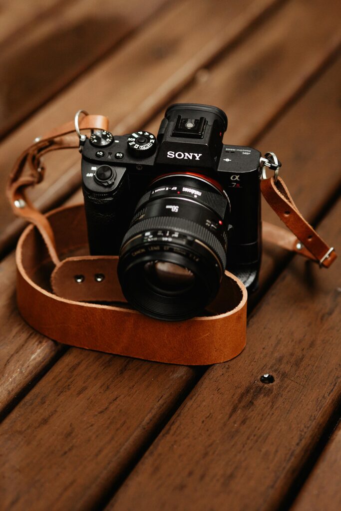 Close-up shot of a mirrorless camera with leather strap on wooden surface, ideal for photography enthusiasts.